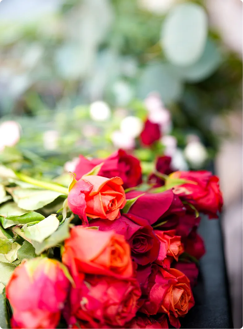 Red and coral roses with eucalyptus laid out during event setup
