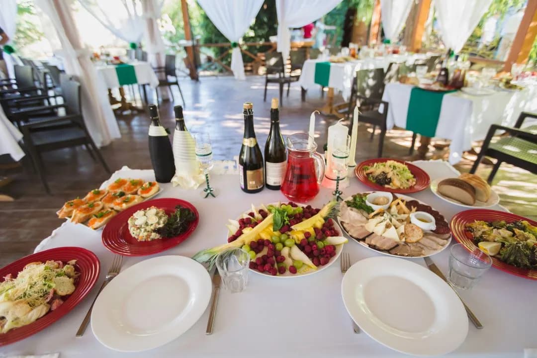 Outdoor reception table set with appetizer platters, a fruit tray, breads and champagne